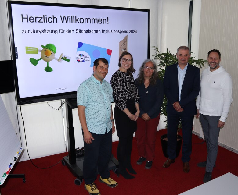 Jury des Inklusionspreises steht vor einer Leinwand