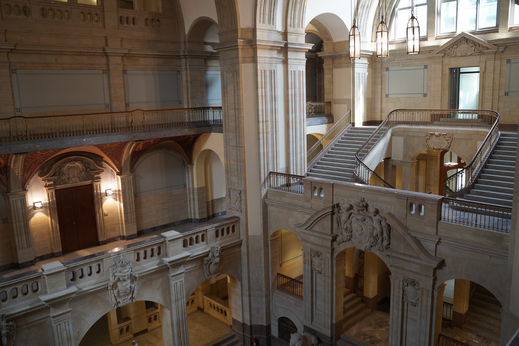 Ein Bild einer großen Halle mit vielen Balkons und Treppen. 