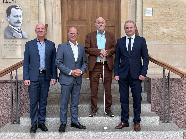 Die Behindertenbeauftragten der drei Bundesländer Sachsen, Sachsen-Anhalt und Thüringen stehen zusammen mit dem Sächsischen Staatsminister für Bundesangelegenheiten auf einer Treppe im Freien. Konkret stehen von links nach rechts die Personen: Dr. Christ