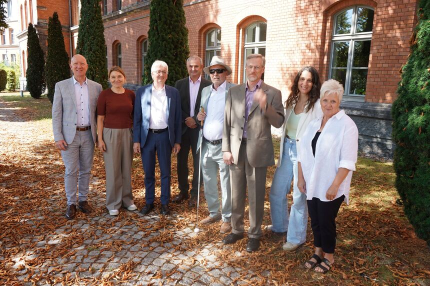 Die Teilnehmer des mitteldeutschen Treffens der Landesbehindertenbeauftragten stehen in einem Halbkreis nebeneinander und lächeln in die Kamera.
