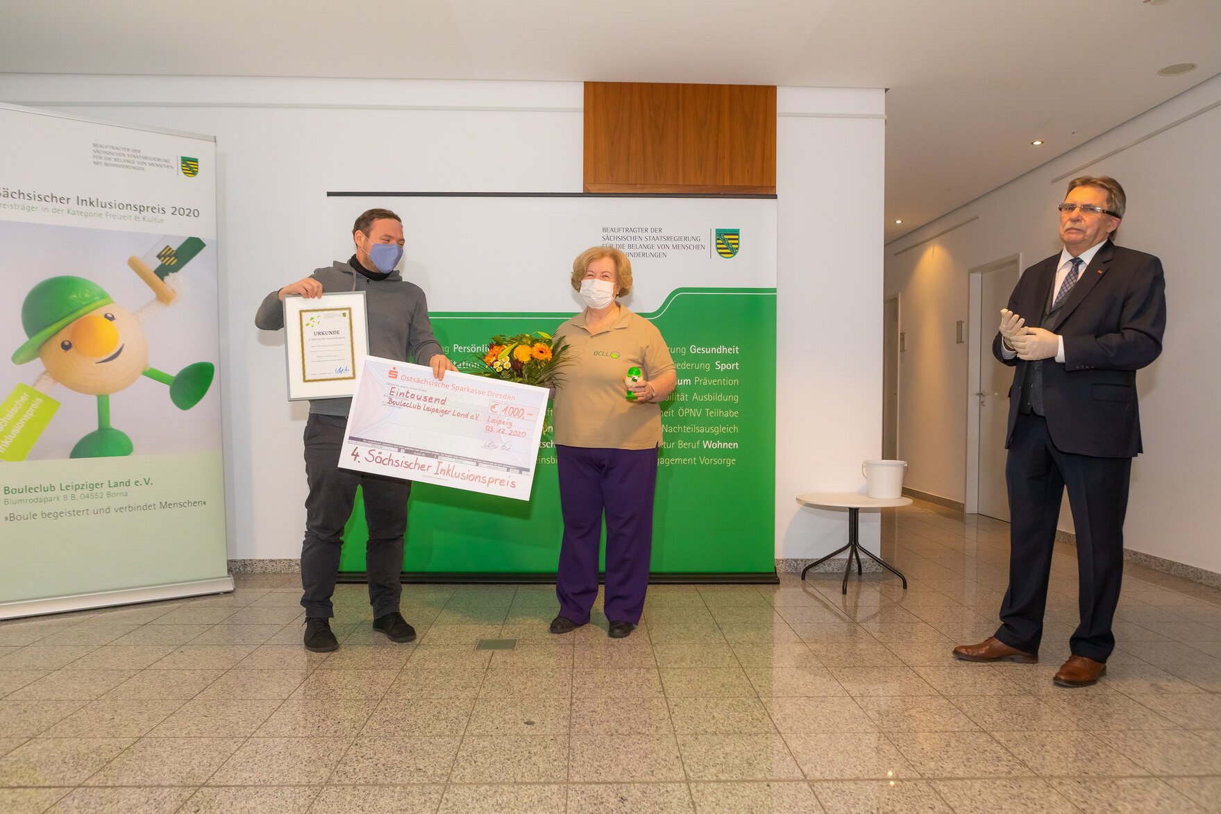 Die Preisträger der Kategorie Freizeit & Kultur, Vertreter des Projektes Bouleclub Leipziger Land e. V., stehen neben dem Beauftragten und halten ihre Auszeichnung - einen Scheck, eine Urkunde, eine Preisfigur und einen Blumenstrauß - in die Kamera.