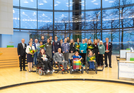 Männer und Frauen stehen im Plenarsaal des Sächsischen Landtages