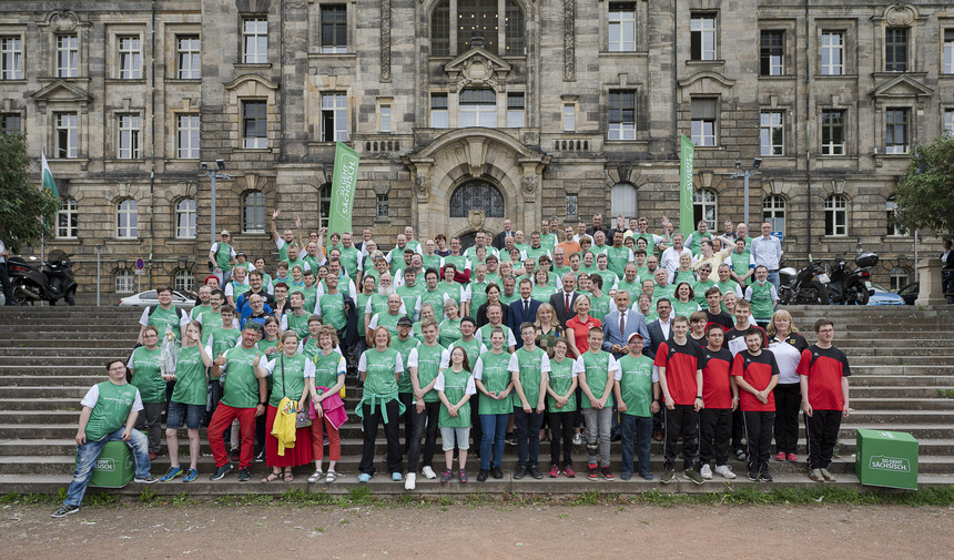 Gruppenfoto mit den Sächsischen Sportlerinnen und Sportler stehen, die zusammen mit Ministerpräsident Kretschmer, seiner Frau, dem Landesinklusionsbeauftragten Welsch und anderen Verbandsvertretern vor der Sächsischen Staatskanzlei stehen. 