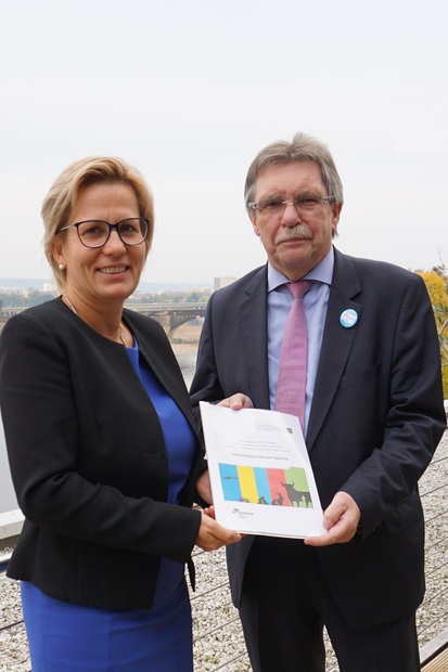 Foto: Sozialministerin Barbara Klepsch und Behindertenbeauftragter Stephan Pöhler stehen nebeneinander und halten gemeinsam das Eckpunktepapier zum Sächsischen Inklusionsgesetz in den Händen.